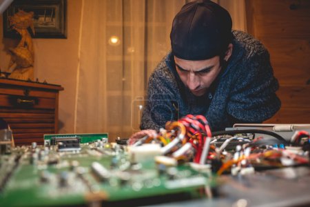 Téléchargez les photos : Expertise de technicien en électronique : un jeune latino réparant un gros équipement électronique sur une table - en image libre de droit