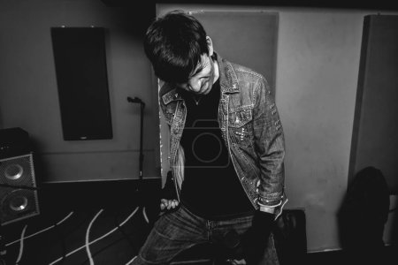 Téléchargez les photos : Jeune chanteur rock passionné et intense déchaînant de l'énergie brute lors d'une performance métal intense dans une salle de répétition (en noir et blanc)) - en image libre de droit