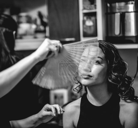 Foto de La belleza de la preparación: un maquillador preparando a una hermosa y joven modelo morena para una sesión de fotos (en blanco y negro) - Imagen libre de derechos