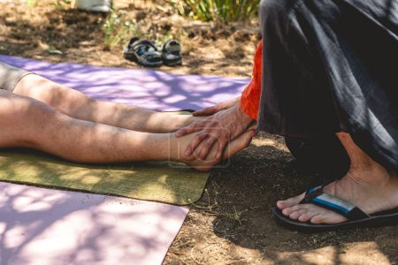 Healing touch : massothérapeute effectue avec sa main un massage des pieds et des jambes dans un environnement naturel