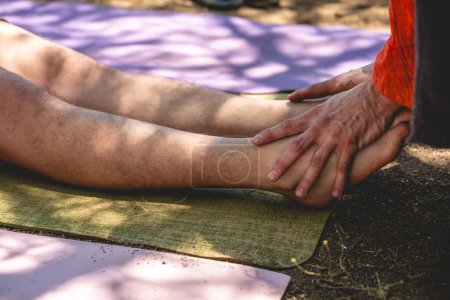 Heilende Berührung: Masseur führt mit der Hand eine Fuß- und Beinmassage in natürlicher Umgebung durch