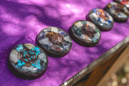 Natural protection: orgonite (orgone) discs, with quartz, metals and other compunds over a purple fabric under sunlight