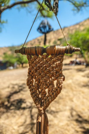 Foto de Artesanal y elaborado con cuidado: intrincada decoración de tela de algodón anudada a mano que se balancea de un árbol en medio de un entorno natural - Imagen libre de derechos