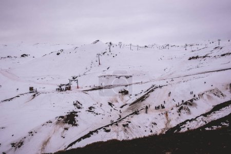 Téléchargez les photos : De joyeux moments d'hiver : remontées mécaniques et petites silhouettes ludiques contre la neige claire dans une belle vue sur la colline - en image libre de droit