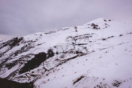 Téléchargez les photos : Moments d'hiver joyeux : petites silhouettes ludiques contre la neige claire dans une belle vue sur la colline - en image libre de droit