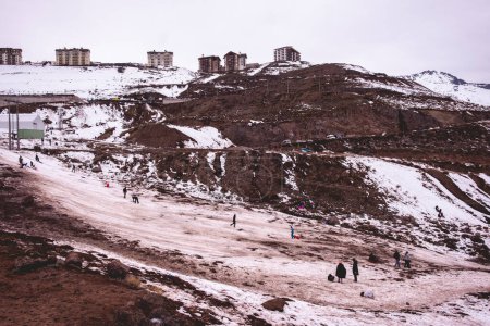 Téléchargez les photos : Moments d'hiver joyeux : petites silhouettes ludiques contre la neige claire dans une belle vue sur la colline - en image libre de droit
