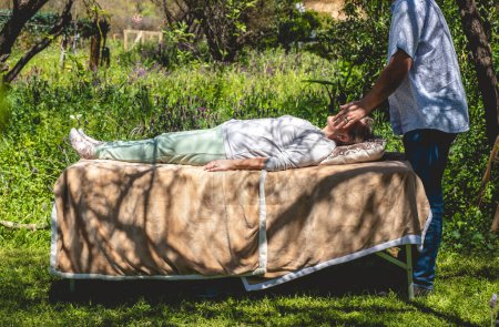 Healing touch: massage therapist's performing with his hand a full body massage in natural surroundings