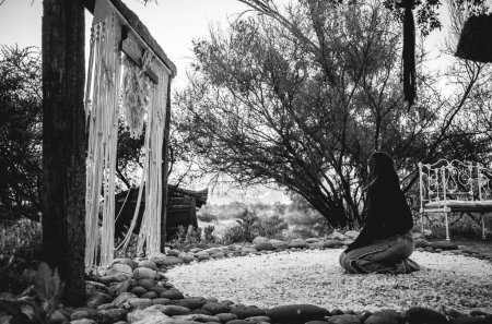 Guérison spirituelle dans la nature : la femme trouve la tranquillité à genoux sur un lit de quartz niché dans la mystique montagneuse (en noir et blanc)