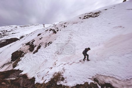 Capturar las alturas: joven fotógrafo camina a través del paisaje de montaña nevado para la toma panorámica perfecta