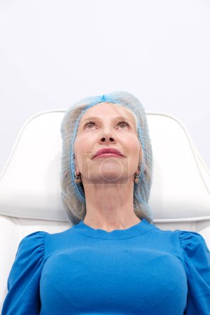 Téléchargez les photos : Vertical picture of smiling mature woman over 50 years undergoing a non-surgical hyaluronic injection procedure, emphasizing the importance of beauty, wellness, and advancements in medical technology - en image libre de droit