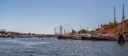 Téléchargez les photos : Stockholm, Suède - 3 juillet 2018 : Vieux navires amarrés à Skeppsholmen. Grona lund et Vasamuseet en arrière-plan. - en image libre de droit