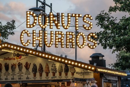 Téléchargez les photos : Alingsas, Suède - 11 juin 2022 : Donuts et churros signent dans un camion de nourriture la nuit. - en image libre de droit