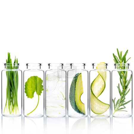 Photo for Homemade skin care with natural ingredients wheat grass ,avocado ,aloe vera ,cucumber twist ,centella asiatica and rosemary in glass bottles isolate on white background. - Royalty Free Image