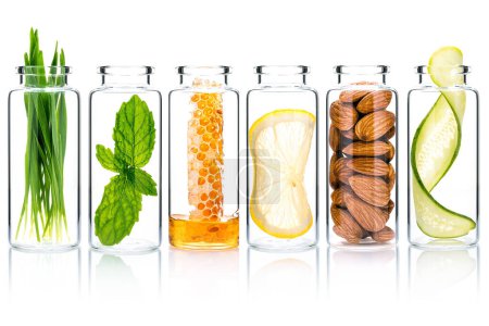 Photo for Homemade skin care with natural ingredients wheat glass ,cucumber slice ,almonds ,honeycomb ,lemon slice and mint leaves in glass bottles isolate on white background. - Royalty Free Image