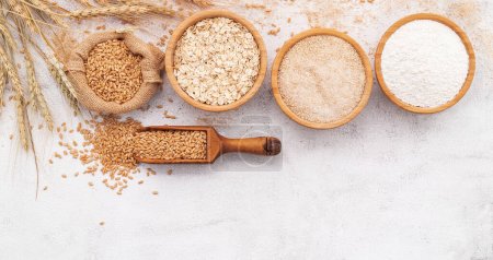 Photo for Wheat grains , brown wheat flour and white wheat flour in wooden bowl set up on white concrete background. - Royalty Free Image