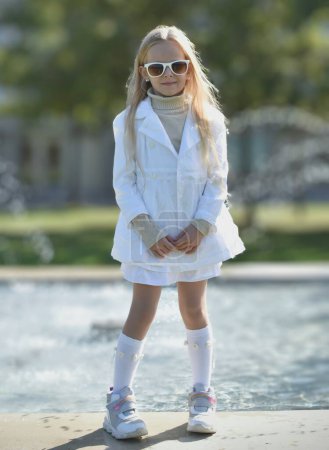 Foto de Chica con el pelo largo y rubio y con ropa blanca y gafas de sol al aire libre - Imagen libre de derechos
