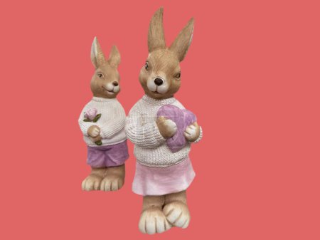 two stone figurines of bunnies with flowers and a heart on a pink background
