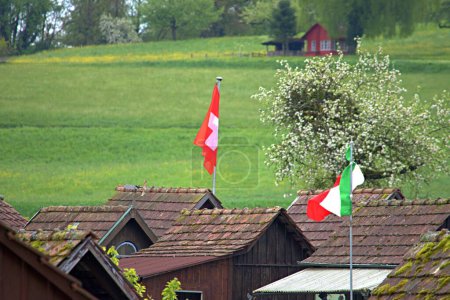 Flagge von Italien und der Schweiz auf den Dächern von Ferienhäusern in der Schweiz