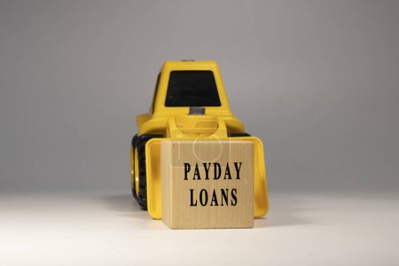 Payday loans text. It is written on a wooden surface. The background is white