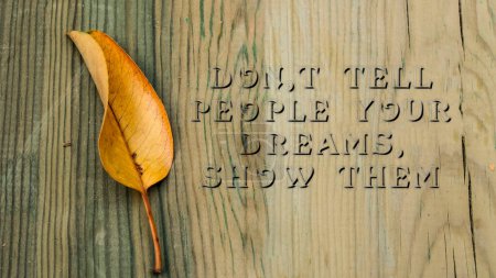 Photo for Dont Tell People Your Dream. Show Them sentence. Written on wooden surface. falling leaf. - Royalty Free Image