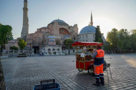 Foto de Carro vendedor tradicional turco Simit Bagel vendedor en el parque cuadrado del sultán ahmet cerca de la mezquita del sultán ahmet. Museo de la mezquita de Santa Sofía visto detrás - Imagen libre de derechos
