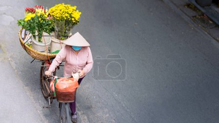 Foto de Vista aérea de una vendedora callejera vietnamita utiliza su bicicleta como un puesto de flores móviles a lo largo de una carretera. emblemático del patrimonio cultural de Vietnam. - Imagen libre de derechos