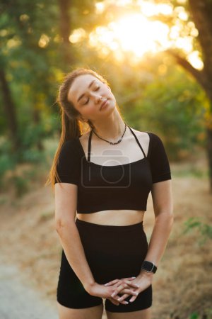 Téléchargez les photos : Jeune femme de fitness faisant des exercices dans la forêt au coucher du soleil, concept de santé et de sport - en image libre de droit