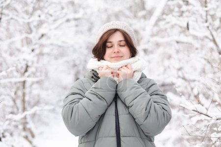 Téléchargez les photos : Jolie jeune femme en vêtements d'hiver parmi les arbres couverts de neige, fille marchant dans la forêt enneigée jouissant d'une belle nature - en image libre de droit