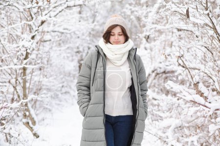 hübsche junge Frau in Winterkleidung zwischen schneebedeckten Ästen, Mädchen, die im verschneiten Wald spazieren gehen und die schöne Natur genießen