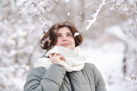 Téléchargez les photos : Portrait de jeune femme regardant vers le haut sur la nature hivernale, jolie belle fille parmi les arbres couverts de neige marchant dans la forêt blanche et profitant - en image libre de droit