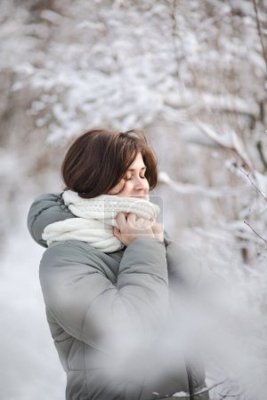 Téléchargez les photos : Jolie jeune femme en vêtements d'hiver parmi les arbres couverts de neige, fille marchant dans la forêt enneigée jouissant d'une belle nature - en image libre de droit