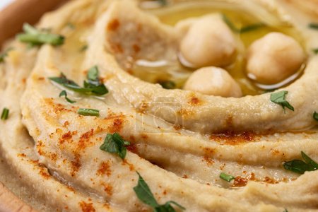 Téléchargez les photos : Chickpea hummus in a wooden bowl garnished with parsley, paprika and olive oil. Close up - en image libre de droit