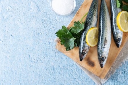 Photo for Raw mackerel fish salt around on blue background. Top view. Copy space - Royalty Free Image