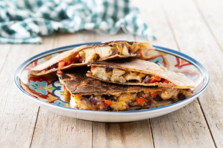 Mexican chicken quesadillas with cheese and peppers on wooden table