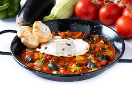 Gemüse Pisto Manchego mit Tomaten, Zucchini, Paprika, Zwiebeln, Auberginen und Ei, serviert in Pfanne isoliert auf weißem Hintergrund