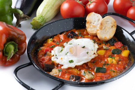 Gemüse Pisto Manchego mit Tomaten, Zucchini, Paprika, Zwiebeln, Auberginen und Ei, serviert in Pfanne isoliert auf weißem Hintergrund