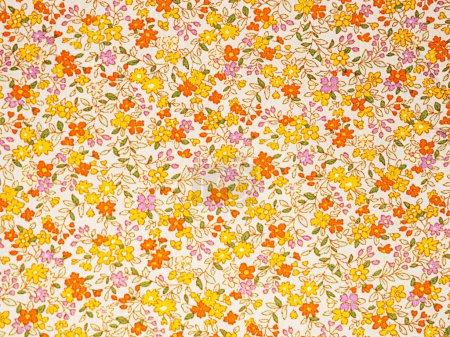 Photo for The fabric is white with a flower of orange, yellow and purple as a background with green leaves - Royalty Free Image