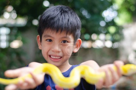 Foto de Asiático chico 6 años de edad retrato, sonriendo con feliz conceptual, llevar azul oscuro camisa y sostener amarillo serpiente - Imagen libre de derechos