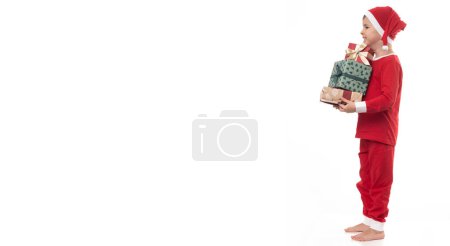 Foto de Muy adorable joven chico con santa claus pijama tener un montón de diversión en foto estudio en aislado blanco fondo. - Imagen libre de derechos