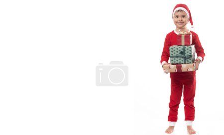 Foto de Muy adorable joven chico con santa claus pijama tener un montón de diversión en foto estudio en aislado blanco fondo. - Imagen libre de derechos