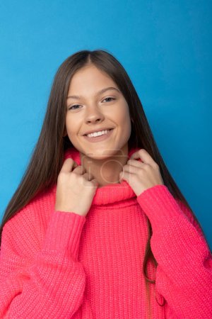 Foto de Bastante adolescente chica es sonriendo en rosa golf en aislado fondo azul. - Imagen libre de derechos
