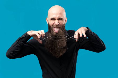 Foto de Peluquero calvo divertido con barba larga y tijeras está posando en el estudio. - Imagen libre de derechos