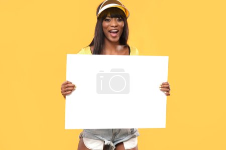 Foto de Atractiva hembra sostiene una pizarra blanca sobre fondo amarillo aislado. - Imagen libre de derechos