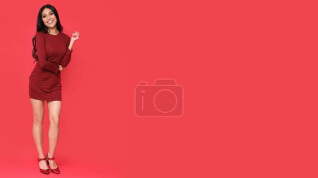 Photo for Perfect brunette in red dress and high heels on red background with place for text. - Royalty Free Image