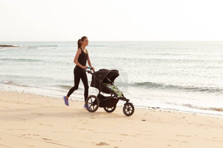 Téléchargez les photos : Belle maman et son fils faisant un jogging matinal sur la plage. - en image libre de droit