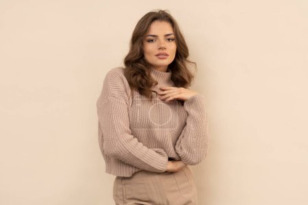 Foto de Estudio de mujer joven atractiva en suéter marrón sobre fondo marrón. - Imagen libre de derechos