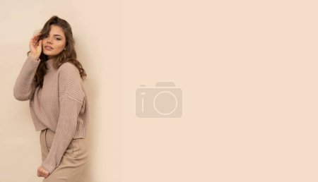 Téléchargez les photos : Plan studio de jolie jeune femme en pull marron sur fond marron. - en image libre de droit
