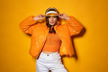Foto de Belleza latina femenina con capucha y chaqueta sobre fondo naranja con sombra. - Imagen libre de derechos