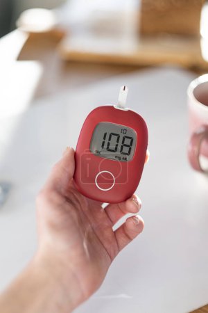 Téléchargez les photos : A woman checks her blood glucose level in the morning. - en image libre de droit