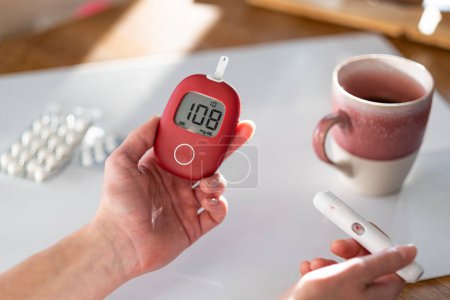 Téléchargez les photos : A woman checks her blood glucose level in the morning. - en image libre de droit